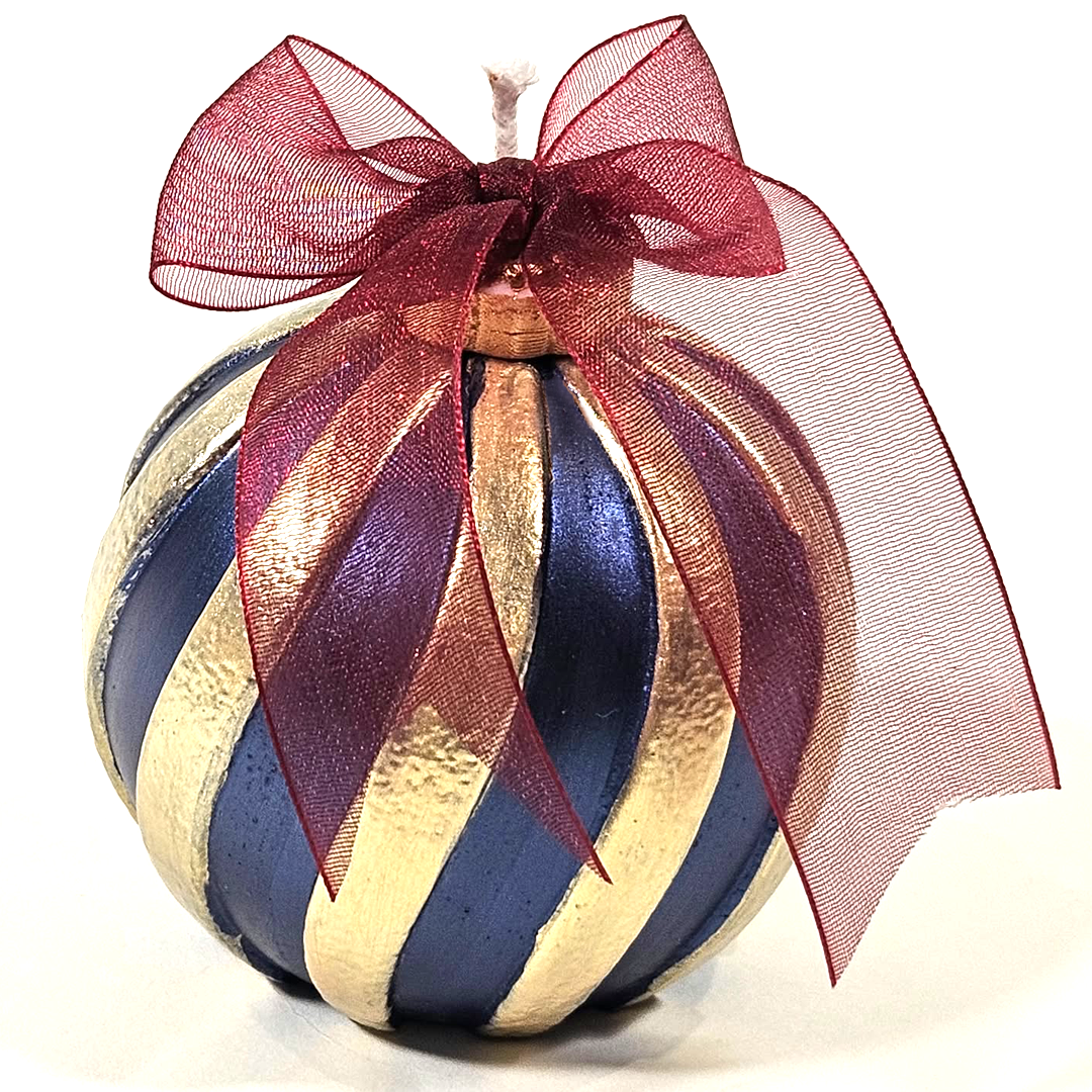 A Blue Scented Wax Baubles Ornament with alternating metallic gold and midnight blue stripes, topped with a large sheer burgundy ribbon bow on a white background.