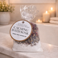 Packaged Epsom salt, lavender, and rose calming bath soak on a marble surface with candles in the background.