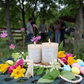 Two candles labeled 'Shenandoah Breeze' on a wooden stand with flowers and beads in the background.