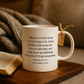 White mug with inspirational quote, open book, and blanket in warm-toned setting