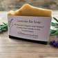 Lavender bar soap with a label on a wooden surface, surrounded by lavender flowers.