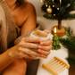 Person scrubbing a bath sponge with soap in a bathroom setting, Christmas tree and decorations in the background.