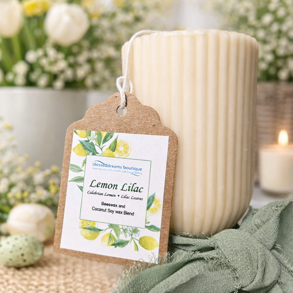 Candle labeled 'Lemon Lilac' with a decorative tag, surrounded by flowers and greenery.