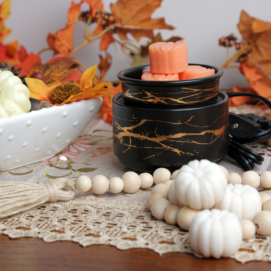 Decorative wax warmer with candles on a table with autumn-themed decor